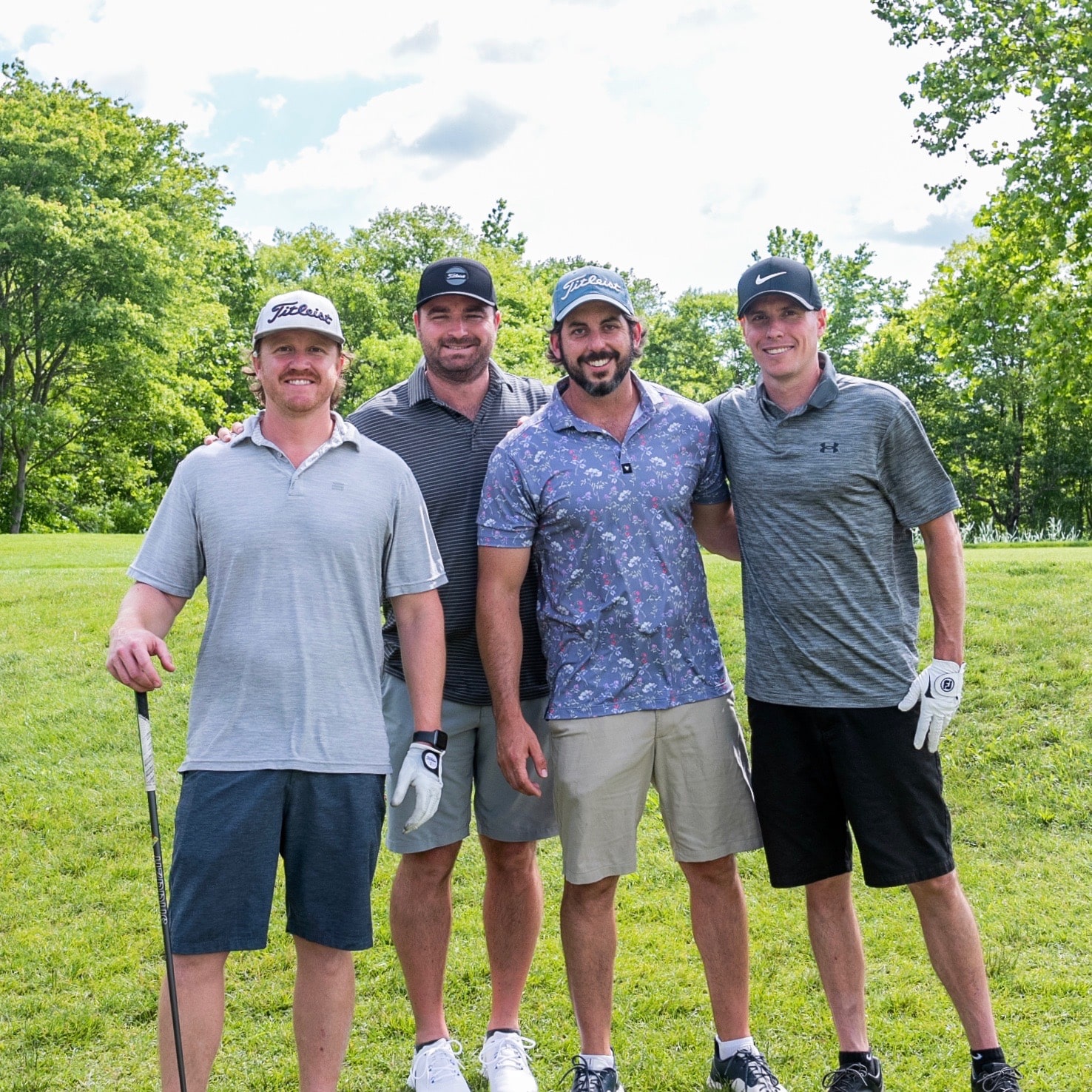 Four men posing together at a golf course