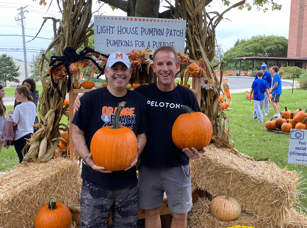 Two people holding pumpkins at the pumpkin patch